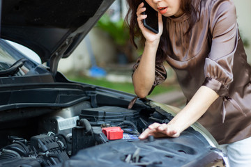 Fototapeta na wymiar asia angry woman looking at broken down car engine and holding mobile phone calling for help