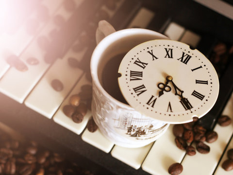 A clock with Roman numerals and a piano, coffee beans