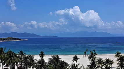 Seascape. Summer day. Beach with clean white sand, palm trees, blue sea, beautiful clouds in the sky.