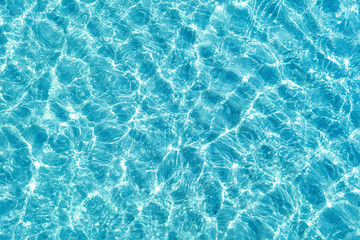 Background shot of aqua water surface. Swimming pool with sunny reflections.