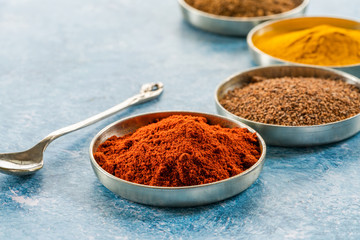 Ground spices in pots - paprika, nutmeg, tumeric and cumin - closeup with selective focus