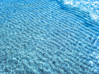 Background shot of aqua water surface. Swimming pool with sunny reflections.