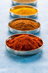 Ground spices in pots - paprika, curry powder, tumeric and chilli powder- closeup with selective focus