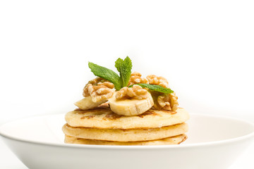 Tortitas con rodajas de plátano y menta sobre un plato blanco sobre un fondo balnco aislado. Vista de frente. Copy space