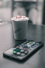 paper cup of coffee on the table, next to the mobile phone