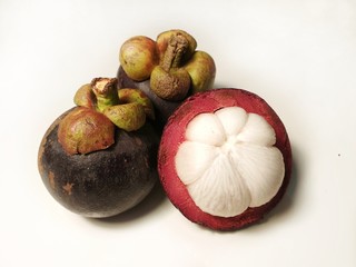mangosteen fruit one cut in half to expose the flesh, on white background