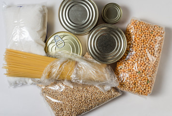 Long-term storage products. Canned meat and fish, spaghetti paste, sugar, dry peas and pearl barley in packs on a white background
