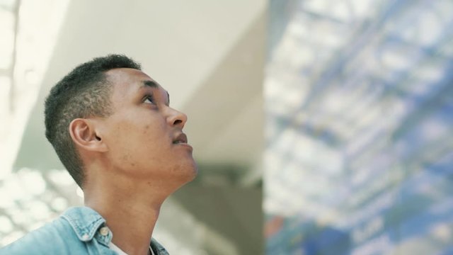 the guy at the airport looks at the board looking for his flight