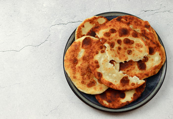 Homemade buttermilk cheese pita on a round plate on a light gray background. Top view, flat lay