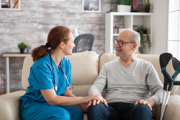 Female doctor with stethoscope in nursing home talking with old patient. - obrazy, fototapety, plakaty