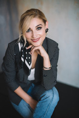 Beautiful young blond woman in jeans with a polka dot jacket and a scarf in her hair in a loft...
