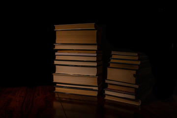 Pile of books on top of an old table in low light.