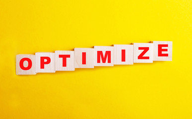 optimize is the word on wooden cubes in red on a yellow background