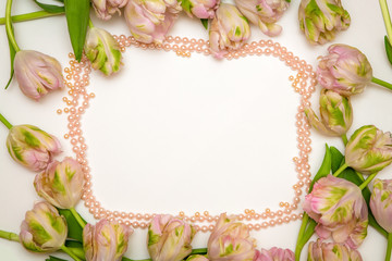Obraz na płótnie Canvas Beautiful tulips in pink pastel color on light white background, top view, frame, border. Lovely greeting card with tulips for Mothers day, wedding or happy event.