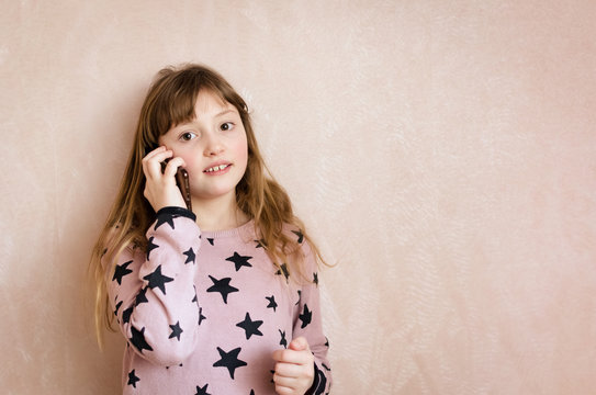 Little girl is talking on a mobile phone.
