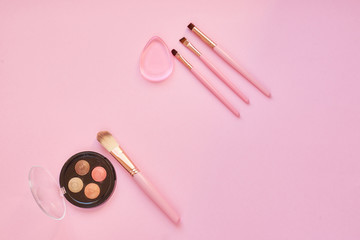 the concept of cosmetics and skin care, cosmetic brush and eye shadow on a pink background