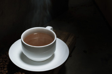 Coffee in a cup and coffee beans in the dark