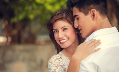 Naklejka premium Young happy smiling attractive couple spending time together outdoors in park in summer. Romantic couple having a date outdoors hugging and laughing