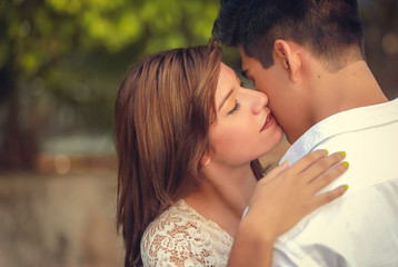 Beautiful young couple kissing outdoor in summer park. Romantic couple in love having a date outside