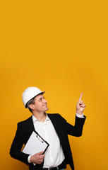 Foreman. Close-up photo of attractive young foreman in a helmet, who is pointing and looking...
