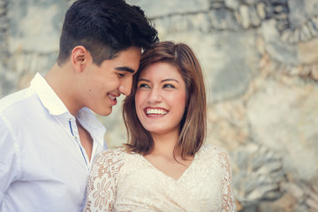 Young smiling attractive couple spending time together outdoors in park in summer time. Romantic couple having a date outdoors hugging and laughing