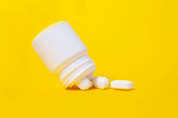 White pills falling from plastic medicine jar.