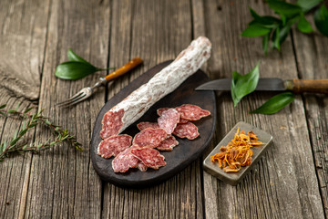 Dried sausage on wooden board with spices chili pepper wooden texture cuisine