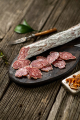 Dried sausage on wooden board with spices chili pepper wooden texture cuisine
