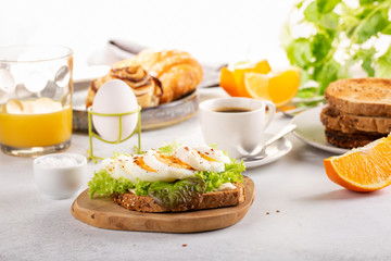 Delicious breakfast with boiled egg on toasted bread, cup of coffee and orange juice.