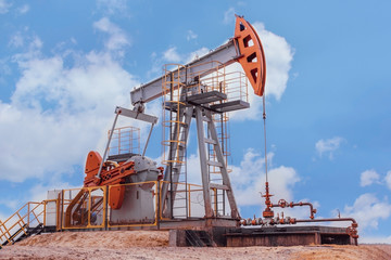 Fototapeta na wymiar oil derrick pumps oil into a well against a blue sky background