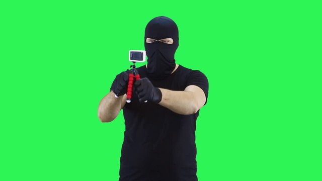 A man in a balaclava takes pictures of himself on an action camera,green screen background