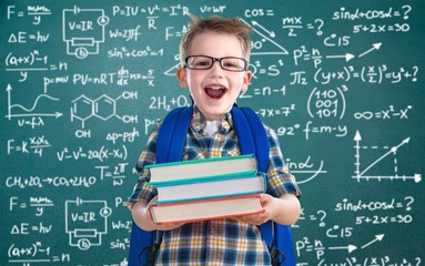 Cute schoolboy in glasses on blackboard background