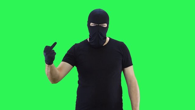 Man in balaclava shows middle finger.,green screen background