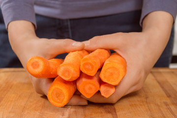 Kobiece dłonie trzymają obrane marchewki.