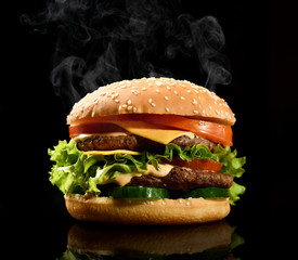 Double burger cheeseburger barbeque sandwich with beef  cheese and fresh vegetables hot with steam smoke on black