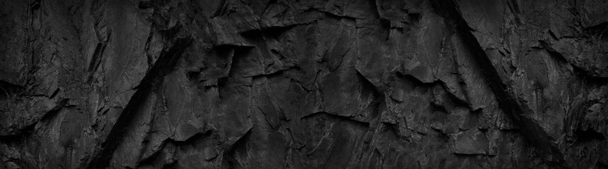 Fototapeta na wymiar Black and white background. Dark stone grunge background. Mountain texture. Close-up. Wide banner with volumetric rock texture.