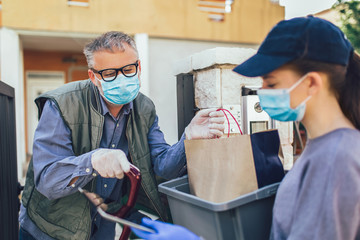 Teenage girl is delivering some groceries to an elderly person, during the epidemic coronovirus,...