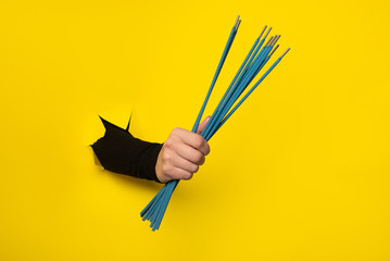 welding electrodes in hand on a torn hole in yellow paper