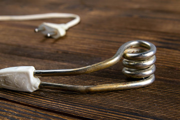 Old immersion water heater on dark wooden background. Close-up