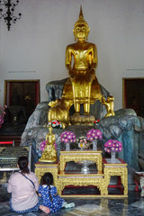 Buda dorado del templo de Wat Pho en Bangkok con personas rezando