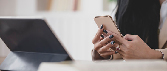 Close up young business women using smartphone near tablet in office , copy space
