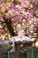 Little blonde girl.  Kid enjoy cherry blossom sakura. Girl on pink flowers sakura tree background. Child enjoy life without allergy. 