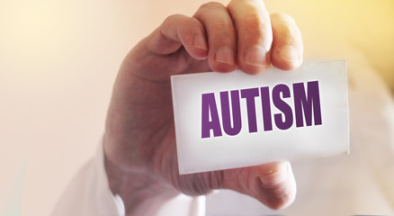 Doctor keeps a card with the name of the diagnosis - autism. Selective focus. Medical concept