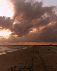 car footprints in the sand on the beach at beautiful sunset