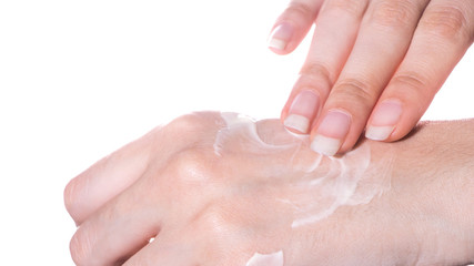 The girl applies a moisturizer or lotion to the skin of the hand on a white background isolated close-up.Spa,skin care at home or in a beauty salon.Treatment and hydration of the skin and dermatology