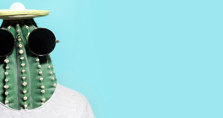 Minimal pop-art collage portrait of green cactus-headed man wearing black round shades and mexican hat on panoramic banner background of cyan color with copy space.
