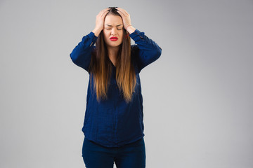 Young caucasian woman suffers from headache, fever, feels sick, ill and weakness isolted on gray studio background. Symptoms of desease or unhealthy lifestyle. Sickness, ilness, sad and upset