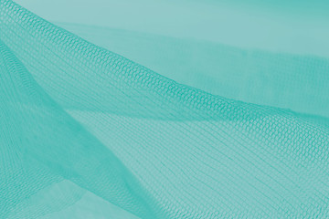 Small mesh fabric on cold green background. Gradient backdrop