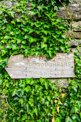 Rustic wooden Public Footpath sign half covered by green ivy