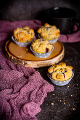 Blaubeeren-Muffins auf Holzscheibe mit dunklem Untergrund